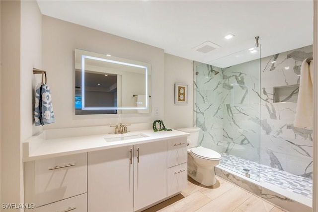 bathroom featuring toilet, a marble finish shower, visible vents, and vanity