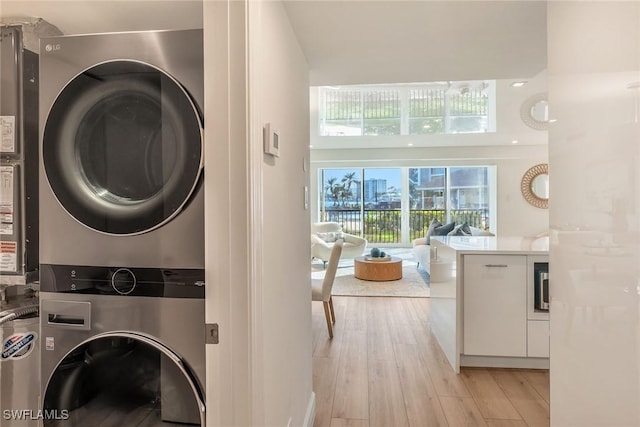 laundry room with stacked washer and dryer, laundry area, and light wood finished floors