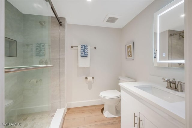 bathroom with toilet, wood finished floors, visible vents, vanity, and a stall shower