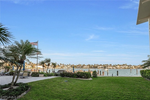 view of yard with a dock, a water view, and a patio