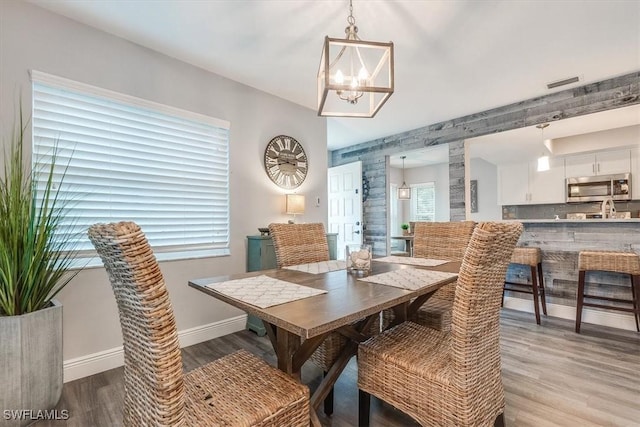 dining room with light wood-style floors, visible vents, a notable chandelier, and baseboards