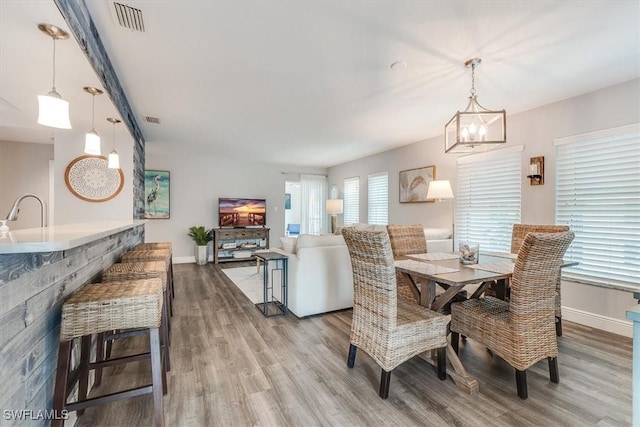 dining space featuring a chandelier, visible vents, baseboards, and wood finished floors