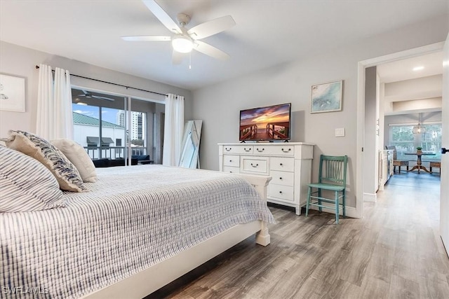 bedroom featuring access to outside, multiple windows, baseboards, and wood finished floors