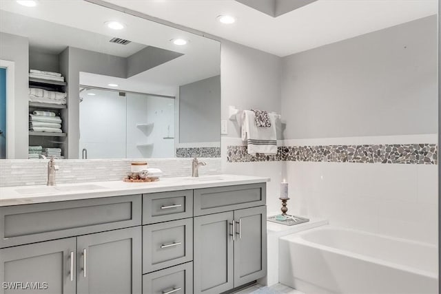 full bath featuring a garden tub, double vanity, a sink, and visible vents