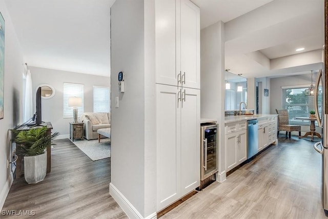 kitchen featuring beverage cooler, light wood-style floors, open floor plan, white cabinets, and stainless steel dishwasher