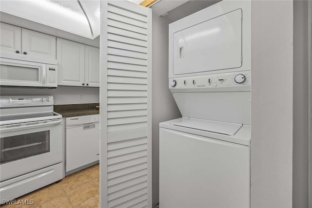 laundry room featuring stacked washing maching and dryer and light tile patterned flooring