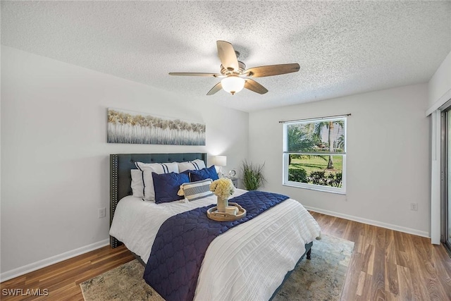 bedroom featuring dark hardwood / wood-style flooring, ceiling fan, and a textured ceiling