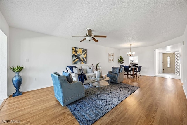 living room with wood-type flooring, ceiling fan with notable chandelier, and a textured ceiling