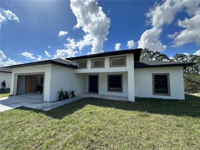 prairie-style home with stucco siding, a shingled roof, concrete driveway, a front yard, and a garage