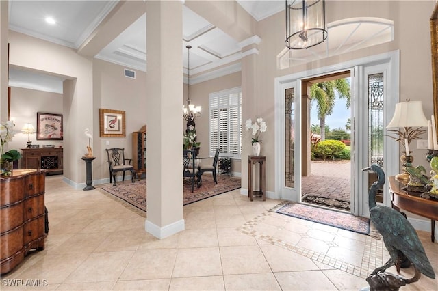 tiled entrance foyer featuring a high ceiling, an inviting chandelier, crown molding, coffered ceiling, and decorative columns