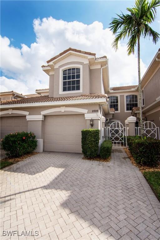 view of front facade with a garage, a tiled roof, decorative driveway, and stucco siding