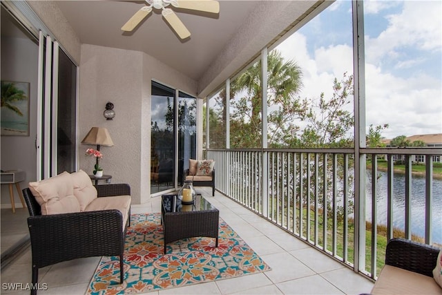 sunroom featuring a ceiling fan and a water view