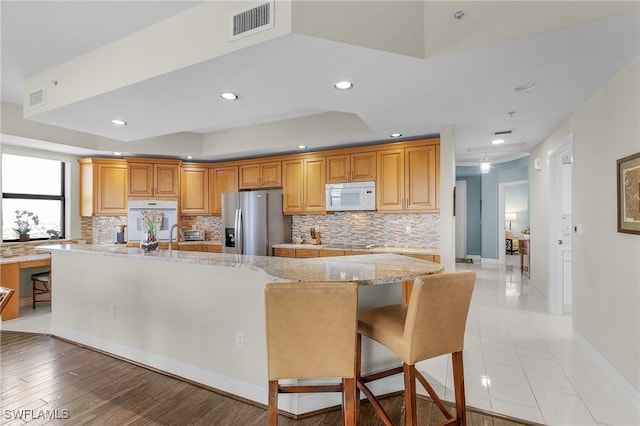 kitchen featuring backsplash, light stone countertops, white appliances, visible vents, and recessed lighting