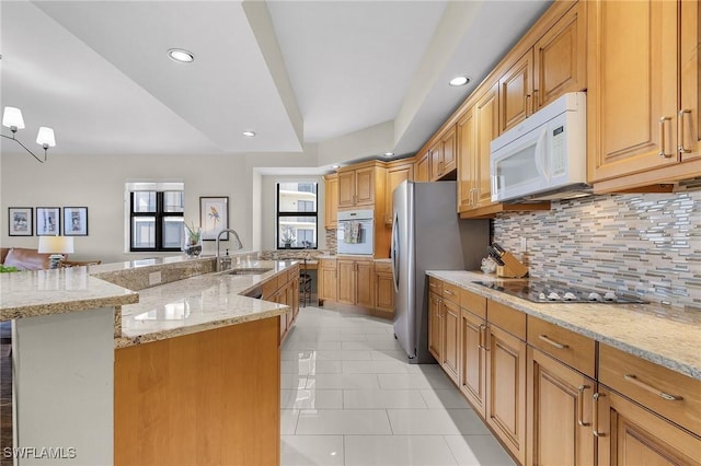 kitchen with light tile patterned flooring, a large island with sink, backsplash, a sink, and white appliances