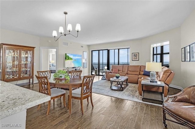 dining space featuring dark wood-type flooring, a wealth of natural light, visible vents, and an inviting chandelier