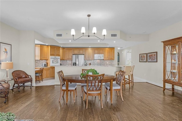 dining room featuring visible vents, a notable chandelier, and wood finished floors