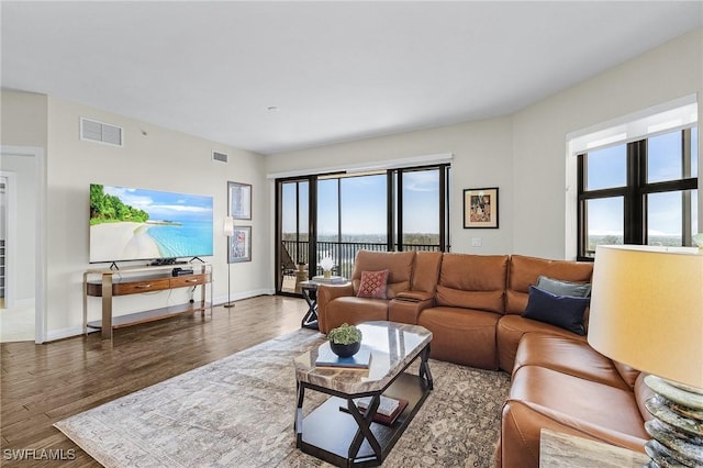 living area with wood finished floors, baseboards, and visible vents