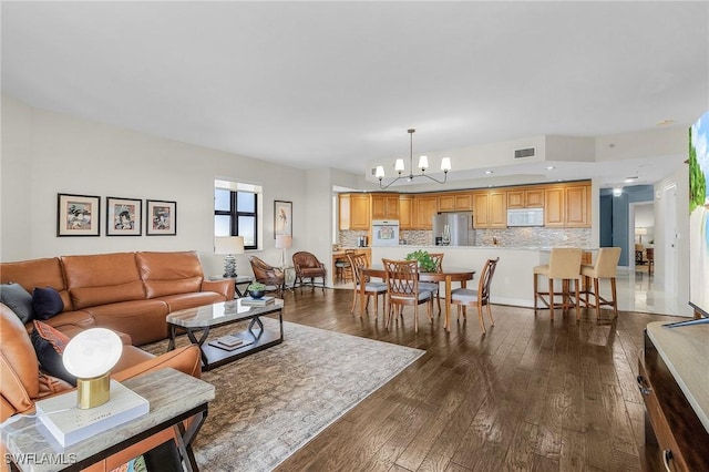 living room with dark wood finished floors, visible vents, and an inviting chandelier