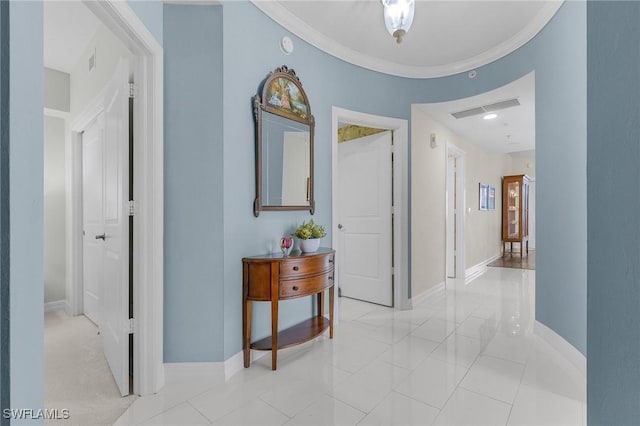 hallway with baseboards, visible vents, and ornamental molding