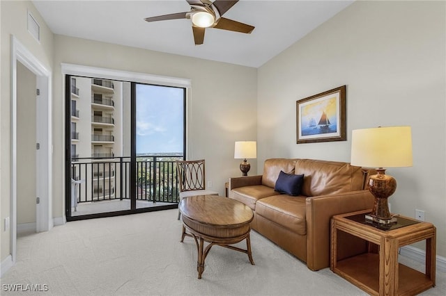 living area featuring baseboards, ceiling fan, visible vents, and light colored carpet