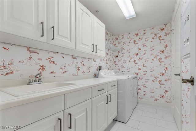 laundry area featuring washer and clothes dryer, a sink, baseboards, wallpapered walls, and cabinet space