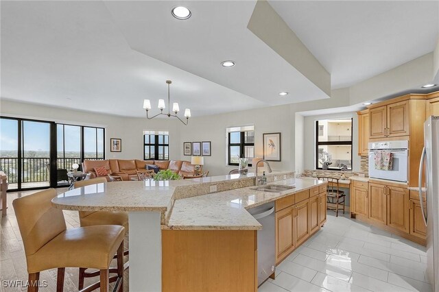 kitchen featuring white oven, a large island with sink, a sink, dishwasher, and open floor plan