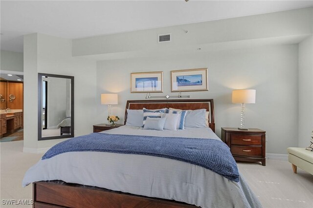 carpeted bedroom featuring baseboards, ensuite bathroom, and visible vents