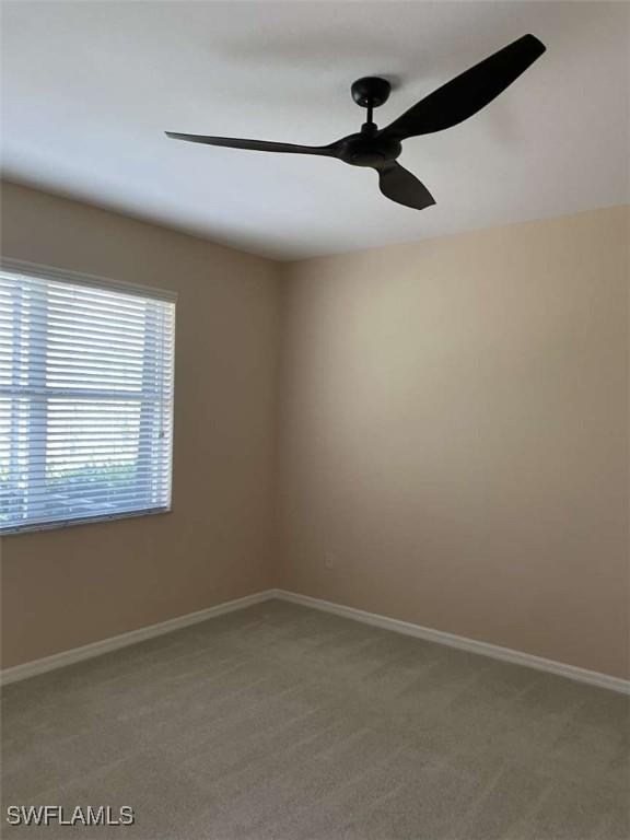 carpeted spare room featuring ceiling fan