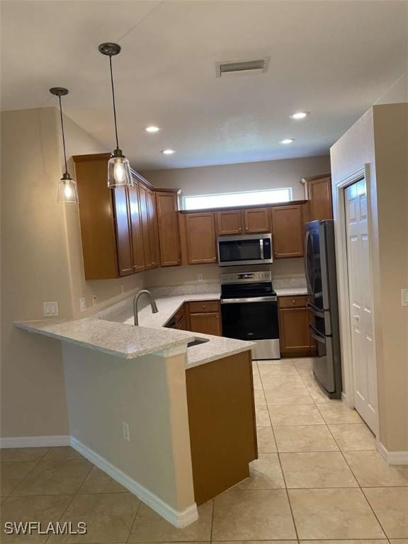 13772 Cleto Dr, Estero, FL 33928 - kitchen with a peninsula, appliances with stainless steel finishes, visible vents, and a healthy amount of sunlight