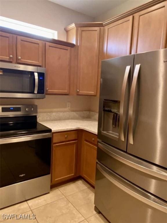 13772 Cleto Dr, Estero, FL 33928 - kitchen featuring appliances with stainless steel finishes, brown cabinetry, light countertops, and light tile patterned floors