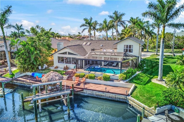 rear view of house with glass enclosure, a patio, boat lift, a yard, and an outdoor pool