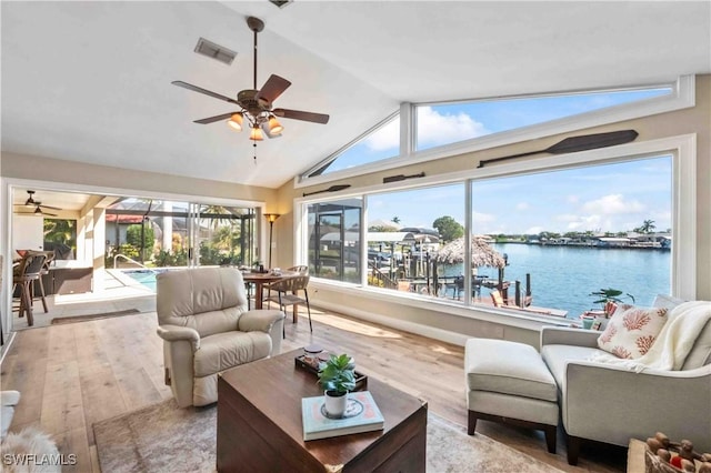 living room with visible vents, a water view, a sunroom, vaulted ceiling, and wood finished floors