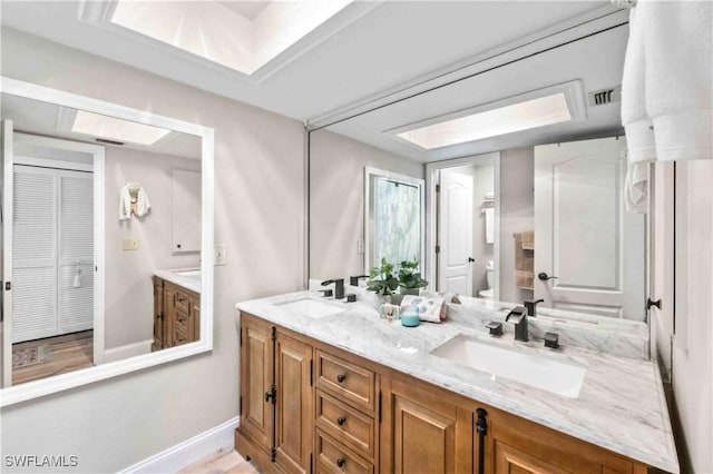 full bath with toilet, double vanity, visible vents, and a sink