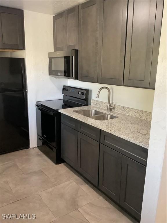 kitchen featuring sink, dark brown cabinets, light stone countertops, and black appliances