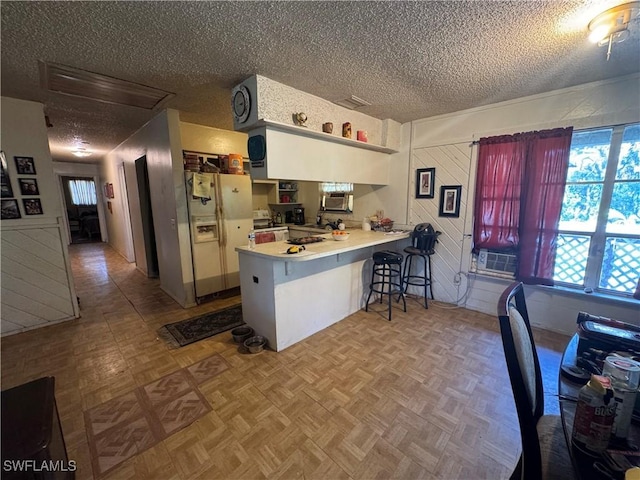 kitchen featuring a breakfast bar, white cabinetry, white fridge with ice dispenser, kitchen peninsula, and light parquet flooring