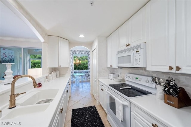 kitchen with white appliances, a wealth of natural light, sink, and white cabinets