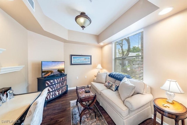 living room with dark wood-type flooring and a tray ceiling