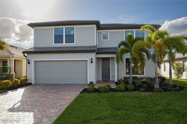 view of front of house with stucco siding, a garage, a front yard, and decorative driveway