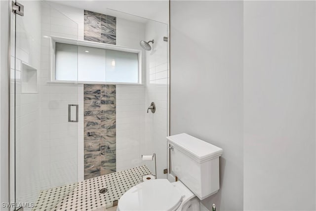 bathroom featuring a shower with shower door and toilet