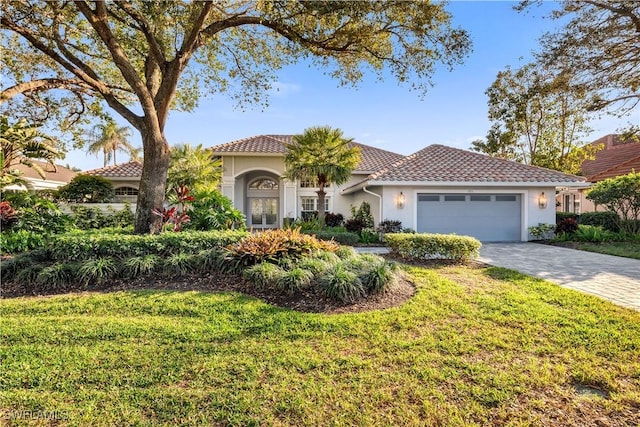 mediterranean / spanish-style home with a garage and a front lawn