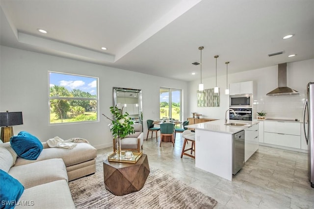 living room featuring a tray ceiling and sink