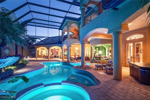 pool at dusk with a patio, ceiling fan, an outdoor hot tub, and glass enclosure