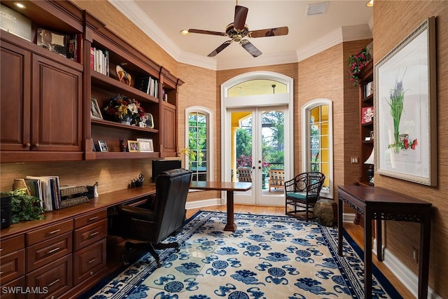 office space featuring french doors, built in desk, ceiling fan, wood-type flooring, and crown molding