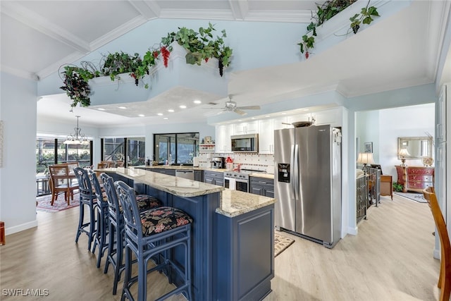 kitchen with crown molding, appliances with stainless steel finishes, light stone counters, white cabinets, and a kitchen bar