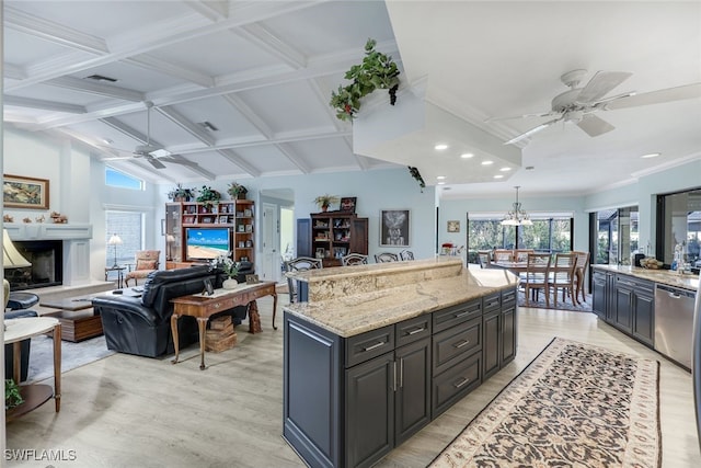 kitchen with beam ceiling, ceiling fan, a center island, and light stone counters