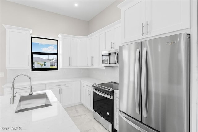 kitchen featuring white cabinetry, appliances with stainless steel finishes, light stone countertops, and sink