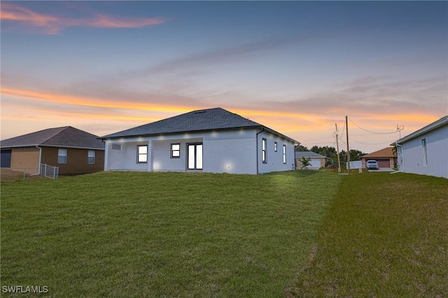 back house at dusk featuring a yard