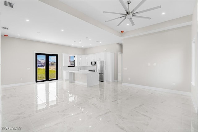 unfurnished living room featuring sink, ceiling fan, and french doors