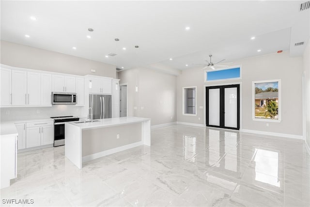 kitchen with pendant lighting, ceiling fan, white cabinetry, stainless steel appliances, and an island with sink