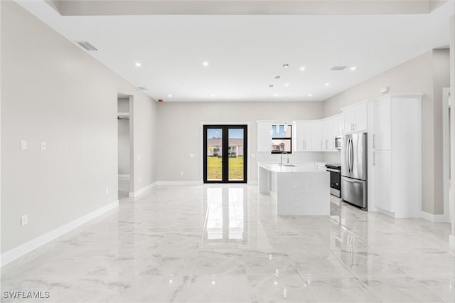 kitchen featuring french doors, sink, white cabinetry, stainless steel appliances, and a kitchen island with sink